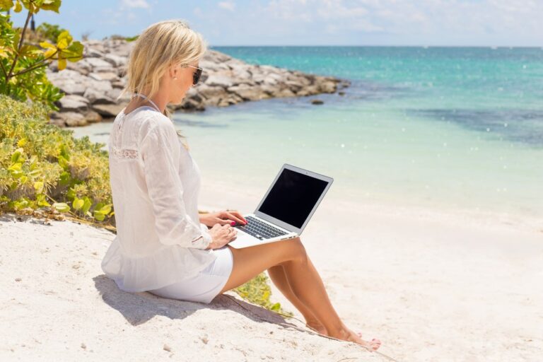women using laptop on beach side